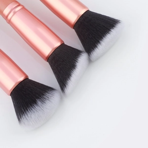 Detailed view of three makeup brushes with soft synthetic bristles and rose gold ferrules
