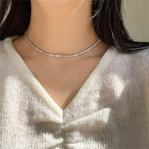 Close-up of a silver-toned tennis necklace with sparkling cubic zirconia on a model