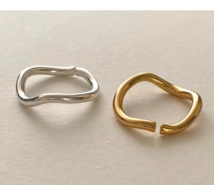 Detailed view of minimalist gold and silver wavy stackable rings on a textured background