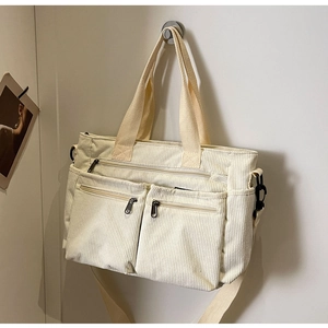 Detail view of beige corduroy tote bag featuring multiple pockets and durable straps