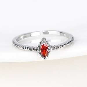 Macro shot of silver twisted band ring with a marquise-cut red zircon on white ceramic