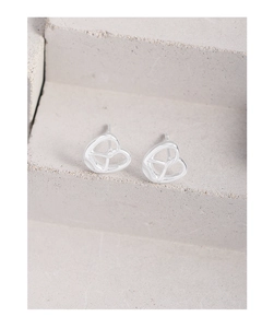 Macro shot of silver heart hollow stud earrings on a minimalist grey stone surface