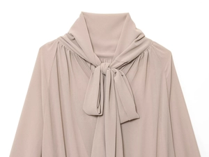 Detalle de blusa rosa empolvado con lazo en el cuello y costuras plisadas en los hombros