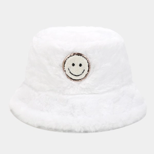 Close-up of white plush bucket hat featuring a sparkly smiley face embroidery patch