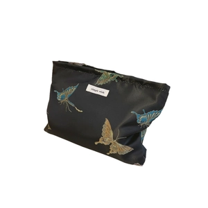Black fabric pouch with butterfly embroidery and simple wish label on white background