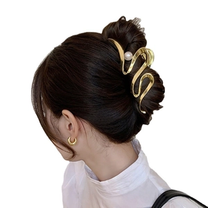 Elegant gold wavy metal hair claw clip with pearl accent on a bun hairstyle