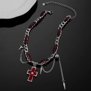 Close-up of gothic red cross pendant and silver chain with metallic spikes on dark background