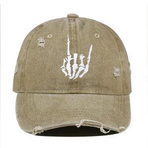 Close-up of rock gesture skeleton hand embroidery on distressed khaki cotton cap