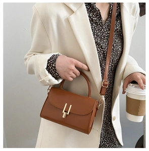 Detail of vintage brown crossbody bag with gold lock buckle and adjustable shoulder strap