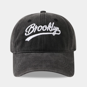Detailed view of white Brooklyn embroidery on washed cotton black baseball cap