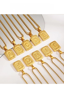 Vue détaillée des pendentifs carrés dorés avec lettres initiales et chaîne torsadée