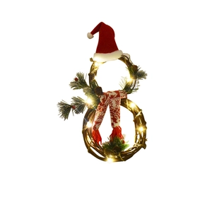 Close-up of snowman shaped Christmas wreath with LED lights, pine cones and red hat