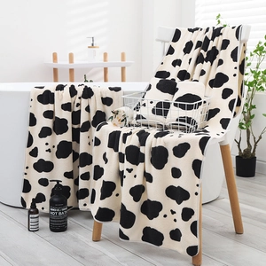 Soft coral fleece towel set with black and white cow print in a cozy bathroom setting