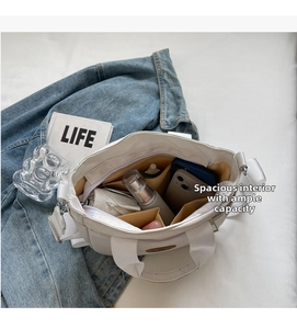 Détail de l'intérieur du sac en toile blanche montrant la grande capacité et les poches
