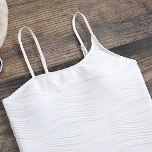 Detail of white textured fabric one-piece swimsuit with thin straps and wavy knit pattern