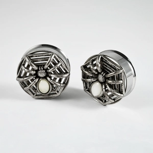 Detail of antique silver spider ear plugs with white shell stone inlay and engraved web