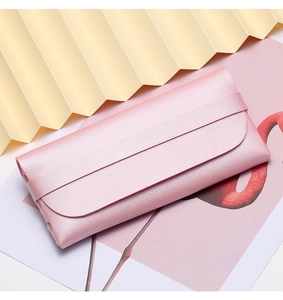 Pink pebbled leather sunglasses pouch with flap closure and strap on aesthetic background