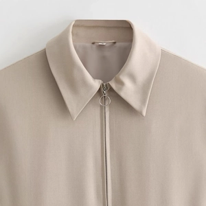 Close-up of khaki zip-up jacket collar with silver metal zipper and ribbed texture