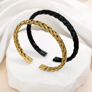 Eleganti bracciali in acciaio inossidabile intrecciato oro e nero su marmo bianco