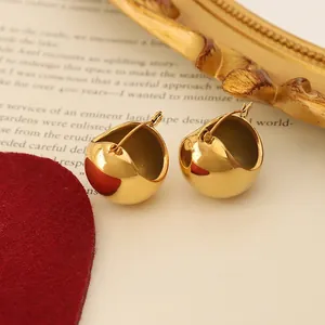Minimalist gold U-shaped ball hoop earrings with polished finish on vintage backdrop
