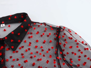 Close-up of black mesh blouse with red heart flocking, collar detail and size S tag