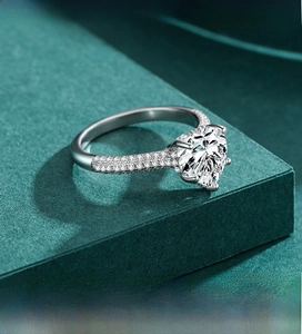 Close-up of S925 sterling silver heart-shaped ring with pavé-set zircons on green stand