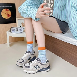 Light blue mesh crew socks with orange ribbed cuffs paired with stylish sneakers