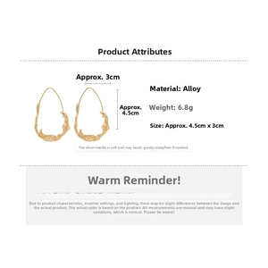 Detail of irregular liquid-metal gold drop earrings featuring fluid texture and silver pins