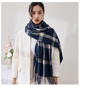 Détail de l'écharpe à carreaux bleu et beige avec franges sur blazer blanc