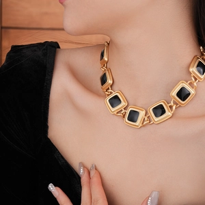 Close-up of vintage gold link necklace with black enamel squares on model neck