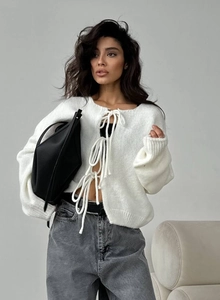 Détail du cardigan blanc avec mailles rayées verticales et fermeture par nœuds à l'avant