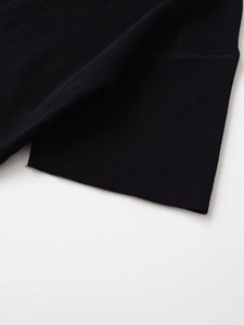 Détail de la manchette en tricot avec des coutures de qualité sur un haut noir à col rond