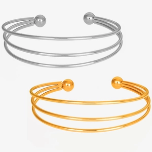 Detail of stacked three-layer open cuff bracelets with spherical ends in gold and silver