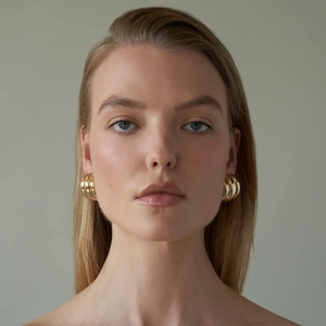 Detailed view of model wearing golden multi-layer spiral hoop earrings in stainless steel
