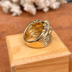 Macro shot of gold-tone wide vine ring with sparkling zircons on a wooden stand