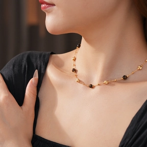 Dettaglio ravvicinato della collana placcata oro con perle occhio di tigre sul collo