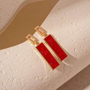Detail view of gold geometric rectangular drop earrings with dark red resin inlay
