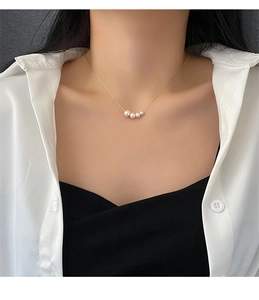 Macro view of four natural white pearls on a minimalist gold titanium steel necklace