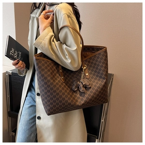 Macro view of monogram pattern tote bag with leather elephant charm and large capacity
