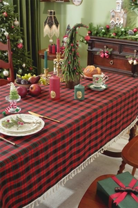 Close-up of festive red plaid tablecloth with cream tassels on a Christmas dinner table