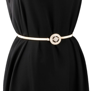 Détail d'une ceinture élastique en métal doré avec une boucle ronde en strass