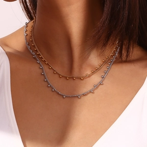 Detail of 18K gold and silver beaded necklaces layered on a woman's collarbone