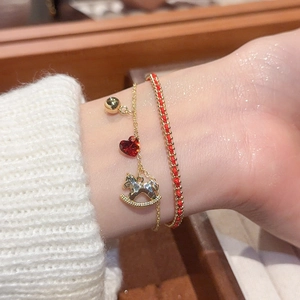 Detail of a golden pony bracelet with red heart gems and braided rope on a wrist