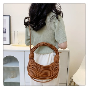 Détail du sac bandoulière camel tressé avec poignée en cuir multicouche unique