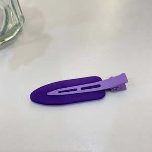 Macro detail of purple matte resin hair clip with metal duckbill clasp on white background