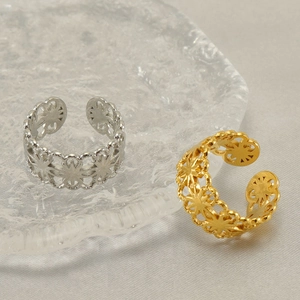 Adjustable hollow flower rings in gold and silver finish on a rippled glass tray
