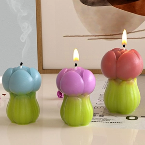 Three tulip-shaped scented candles in blue, purple, and pink on green leaf bases
