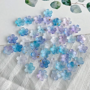 Macro view of blue and purple resin flower beads with golden accents on white fabric