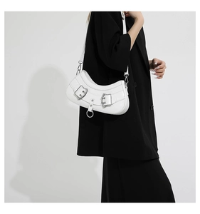 Close-up of white leather underarm bag with decorative silver metal buckle on black suit