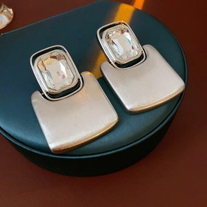 Macro shot of rectangular crystal earrings with brushed silver geometric metal details